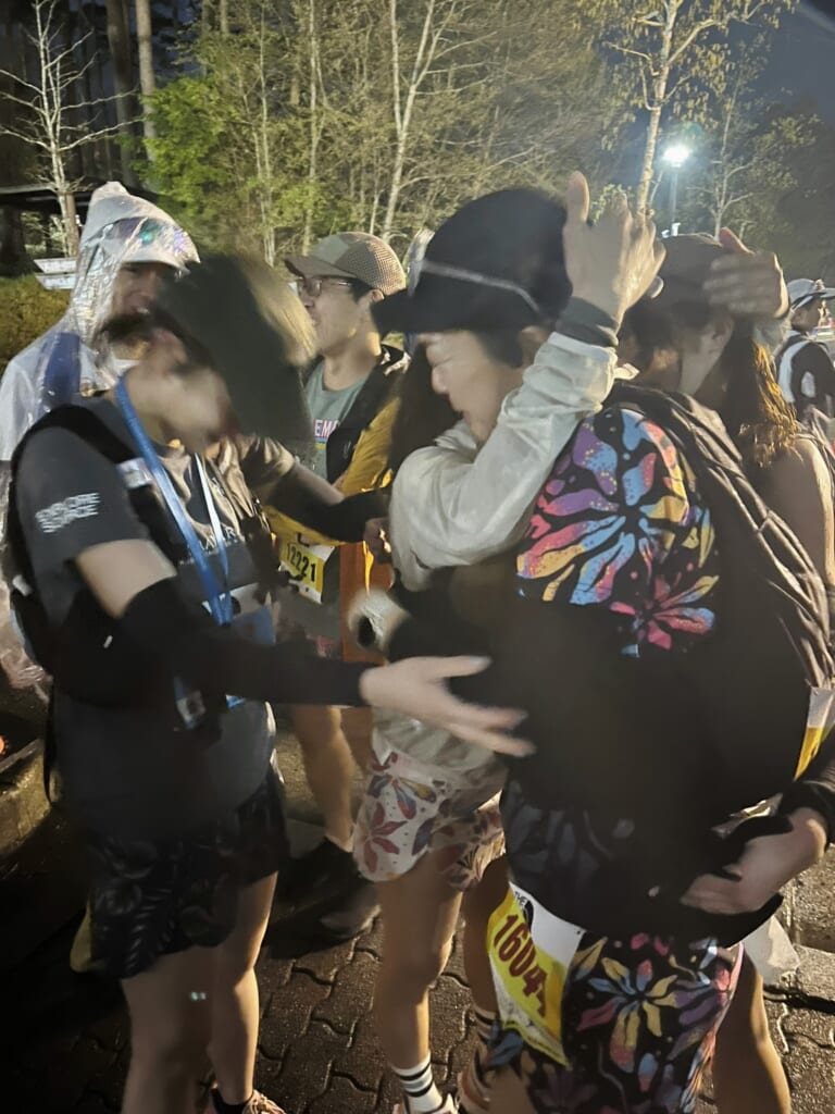 ウルトラマラソン100kmを走り終え、仲間と抱き合うランナーたち